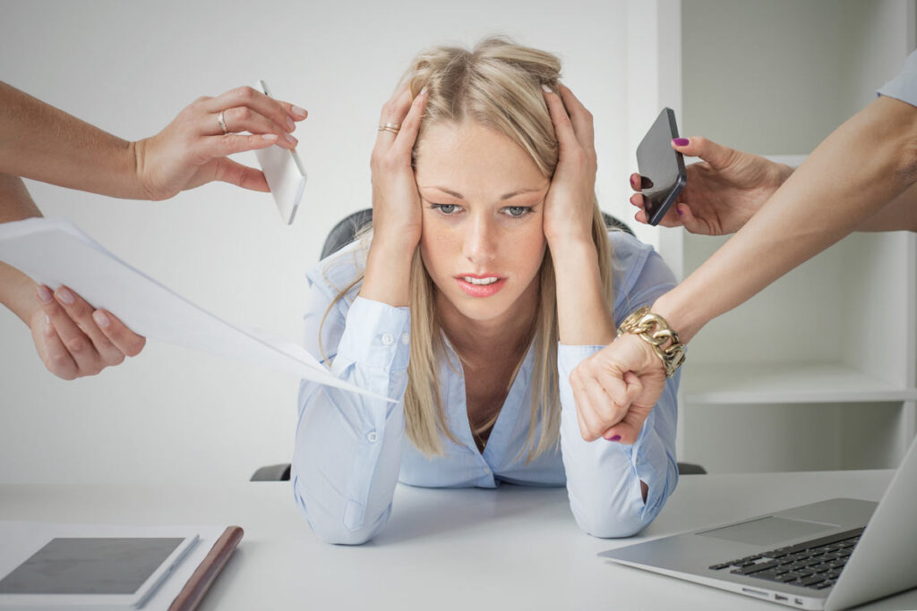 Image symbolique de la pression au travail : femme au bureau entourée de sollicitations